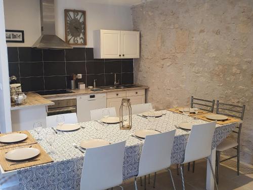 une cuisine avec une table à manger et des chaises blanches dans l'établissement Demeure restaurée avec chambres privatives, proche Loire, vignes et activités outdoor - FR-1-590-240, à Beaulieu-sur-Loire