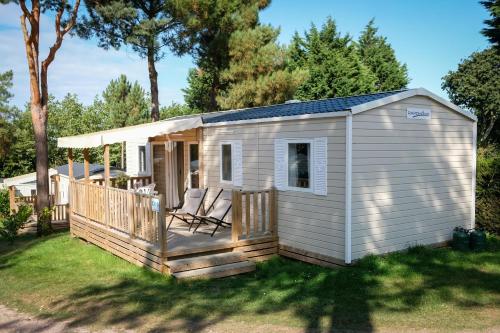 una casa pequeña con porche y terraza en Camping les Lacs d'Armagnac, en Bretagne-dʼArmagnac