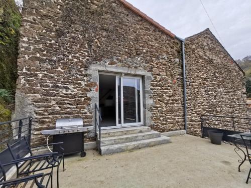 a brick building with a patio and a grill at Gîte cosy avec jeux et terrasse à Auzon - FR-1-582-338 in Auzon