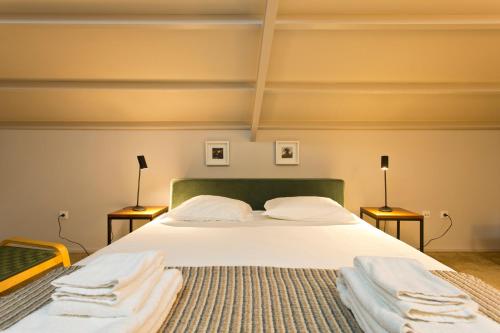 a bedroom with a bed with white sheets and two lamps at RVA - Gustave Eiffel Apartments in Porto