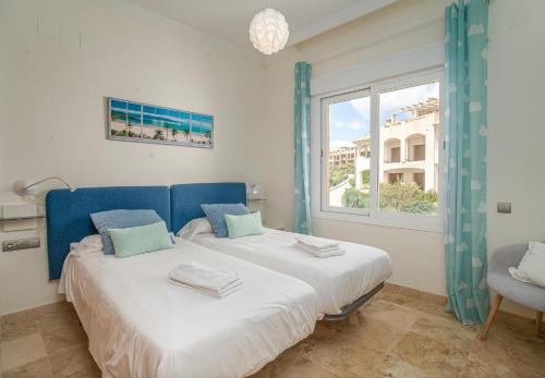 a bedroom with a blue bed and a window at Alta Vista Alcaidesa 2251 in La Alcaidesa