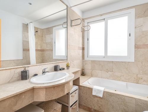 W łazience znajduje się umywalka, wanna i lustro. w obiekcie Alta Vista Alcaidesa 2251 w mieście La Alcaidesa