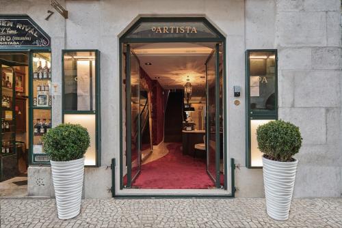 two white vases with plants in front of a store at O Artista Suites by Europe in Lisbon