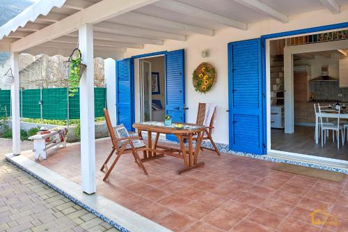 a patio with blue doors and a table and chairs at Violisa Charme in Castellammare del Golfo