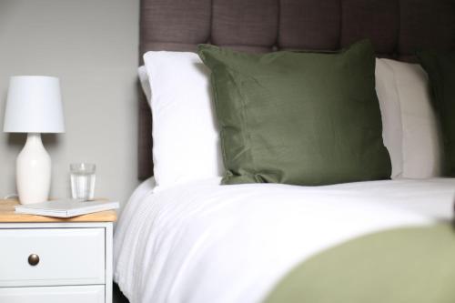 Cama blanca con almohada verde y mesita de noche en Bank Place, en Crieff