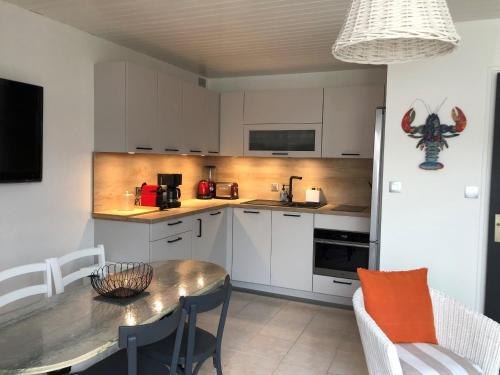 une cuisine avec des armoires blanches et une table et des chaises dans l'établissement Studio rénové à deux pas de la plage des Lutins - Terrasse privée, parking et animaux acceptés - FR-1-426-515, à Noirmoutier-en-l'lle