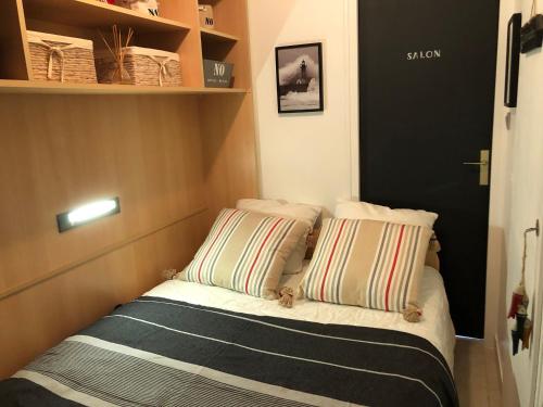 ein kleines Bett mit zwei Kissen in einem kleinen Zimmer in der Unterkunft Gîte Noirmoutier-en-l'Île, 2 pièces, 2 personnes - FR-1-426-515 in Noirmoutier-en-l'lle