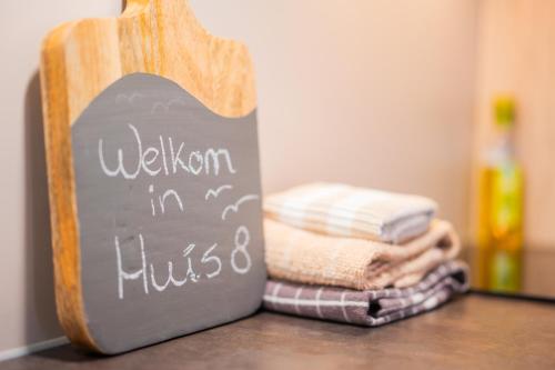 un cartel de pizarra en una mesa con un montón de toallas en Huis 8 Studio's en Katwijk aan Zee