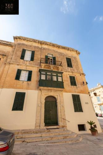 an old brick building with a door and a balcony at Palazzo EL Cattedrale in historic MDINA by 360 Estates in Mdina