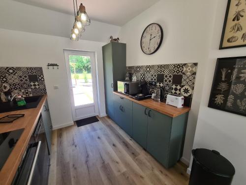 une cuisine avec un comptoir et une horloge au mur dans l'établissement Gîte en Sologne au calme avec étang, proche d'Orléans et châteaux, idéal randonnées et pêche - FR-1-590-242, à Vannes-sur-Cosson