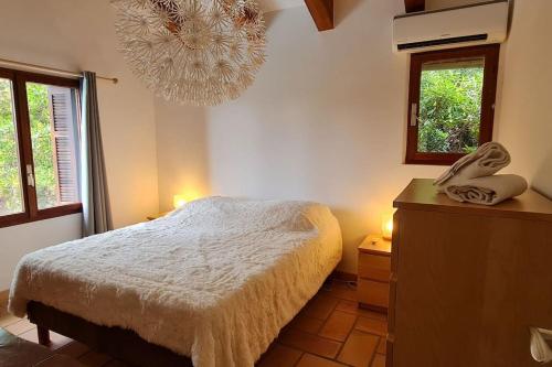 um quarto com uma cama e um lustre em La Bergerie La Belle Epoque, piscine et plage em Saint-Florent