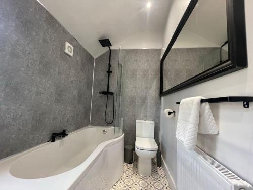 a bathroom with a white tub and a toilet at Perfect for Contractors with on site parking in Brettell Lane