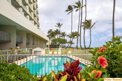 uma piscina em frente a um edifício com palmeiras em Beachfront Condo with AC em Laie