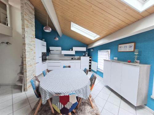 une cuisine avec une table avec des chaises et des murs bleus dans l'établissement Appartement Cosy au Centre-Ville - Idéal pour Explorer Nancy et Verdun! - FR-1-585-84, à Bar-le-Duc