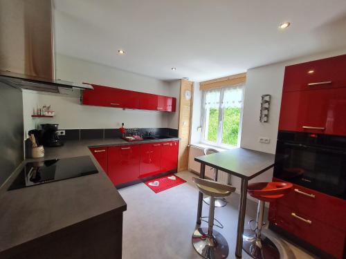 une cuisine avec des armoires rouges et un comptoir noir dans l'établissement Charmant appartement 85 m² près des pistes, terrasse et parking privé, équipements complets. - FR-1-589-410, à La Bresse