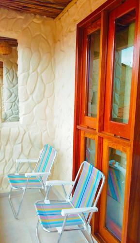 two chairs sitting on a porch next to a building at Japaratinga Suites in Japaratinga