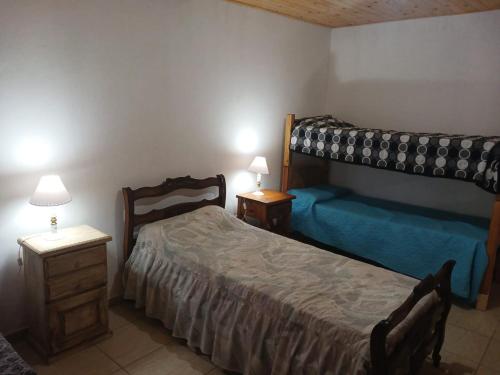 ビージャ・デル・ディケにあるCabaña Villa del Diqueのベッドルーム1室(ベッド2台、テーブル2台、ランプ2つ付)