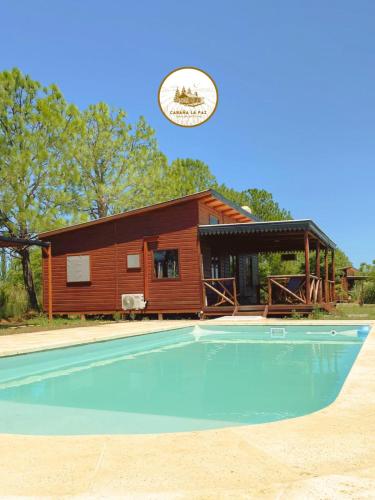 a log cabin with a swimming pool in front of it at Cabaña La Paz in San Andrés de Giles