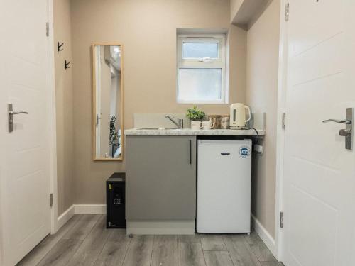 a small kitchen with a sink and a refrigerator at Private double bedroom with bathroom and amenities in Harrow
