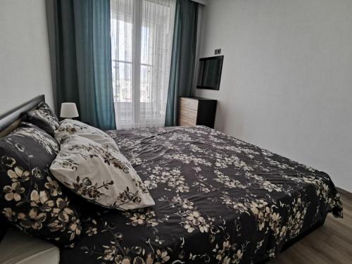 ein Schlafzimmer mit einem Bett mit einer schwarzen Decke und Kissen in der Unterkunft Oak Sky Apartment Spa & Fitness in Skopje