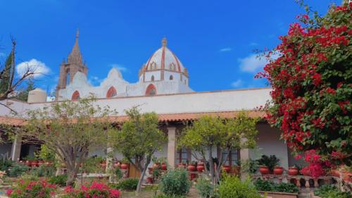 un edificio con alberi e fiori in primo piano di Hacienda de Comodejé a Huichapan