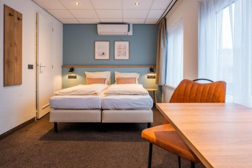 een slaapkamer met een bed en een houten tafel bij Huis 8 Studio's in Katwijk aan Zee