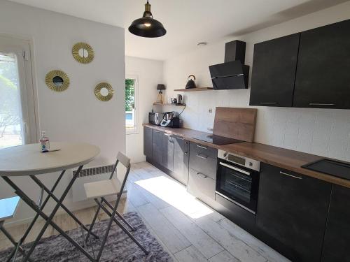 une cuisine avec une table et une petite table, ainsi qu'une table et un porte-table dans l'établissement Gîte tout confort avec jacuzzi, proche Loire et forêt d'Orléans, idéal pour séjours nature et détente - FR-1-590-253, à Ouzouer-sur-Loire