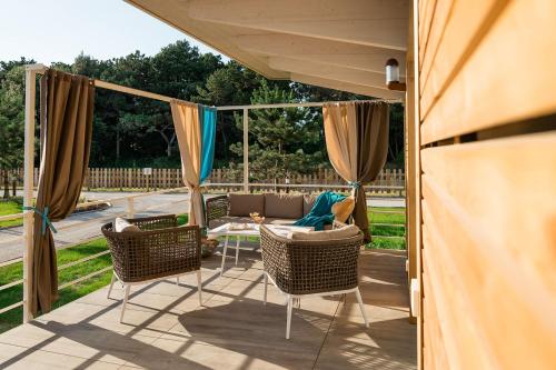 a patio with chairs and a couch and a table at Lino delle Fate Eco Resort in Bibione