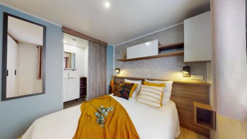 a bedroom with a large white bed with yellow pillows at Camping SIBLU - La réserve in Gastes