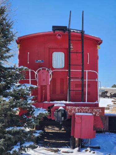 a red train car sitting on the tracks in the snow at The Canyon Motel & RV Park in Williams
