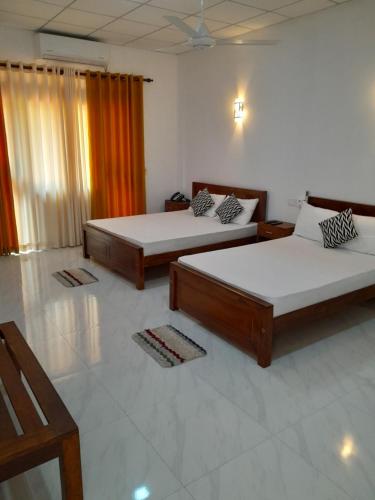 two beds in a room with two tables at Sisila Guest House in Anuradhapura