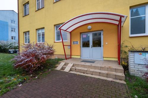 a yellow building with an arched doorway and a door at Apartmán Esser 3 in Milovice