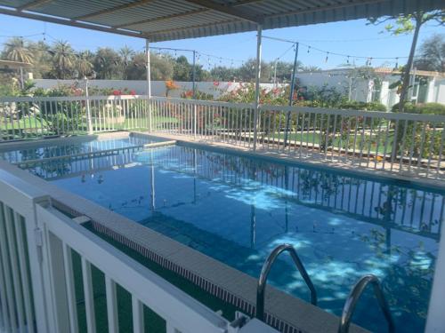 a swimming pool on a balcony with a white fence at Noor Farm Stay 5BHK in Khor Fakkan