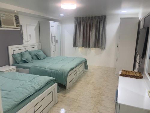 a bedroom with two beds and a flat screen tv at Noor Farm Stay 5BHK in Khor Fakkan