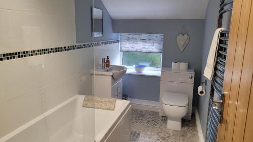 a bathroom with a tub and a toilet and a sink at Coatham Cottage in Barton