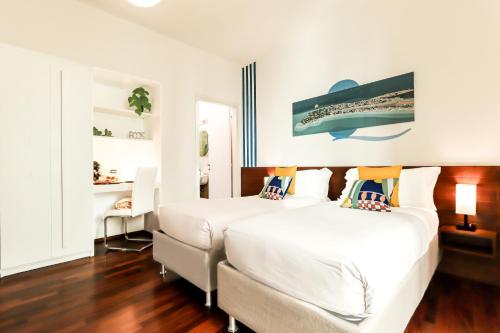 カリアリにあるB&B Qaralの白い壁とウッドフロアの客室で、ベッド2台が備わります。