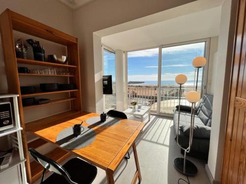 ein Wohnzimmer mit einem Tisch und einem großen Fenster in der Unterkunft Studio magnifique vue mer et port in Valras-Plage