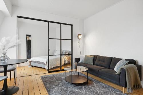 ein Wohnzimmer mit einem Sofa und einem Bett in der Unterkunft New Yorker 2 BR lejlighed tæt på Aalborg Centrum in Aalborg