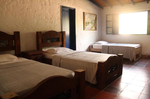 a room with three beds and a window at Hermosa Finca La Rochela, Santa fe de Antioquia in Santa Fe de Antioquia