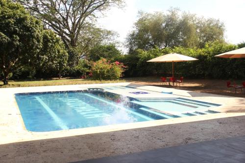 a swimming pool with an umbrella and tables and chairs at Hermosa Finca La Rochela, Santa fe de Antioquia in Santa Fe de Antioquia