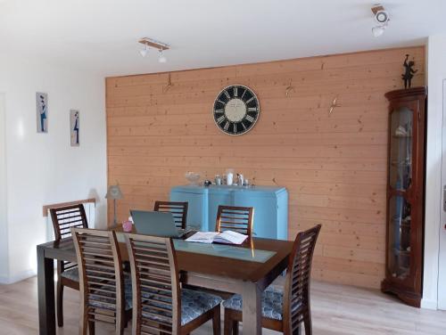 une table à manger avec des chaises et une horloge murale dans l'établissement Maison de pécheur a Barfleur, à Barfleur