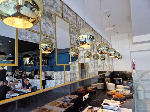 a restaurant with people sitting at tables and chandeliers at Hotel White in Krynica Morska