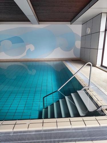 an indoor swimming pool with blue water and stairs at Ferienwohnung - Apartment Pichlarn Holiday in Aigen im Ennstal