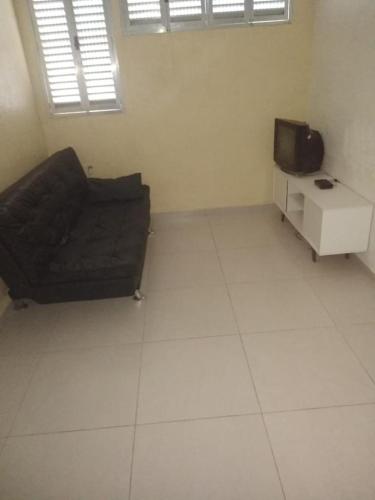 a living room with a couch and a tv at UINQUEND in São Vicente