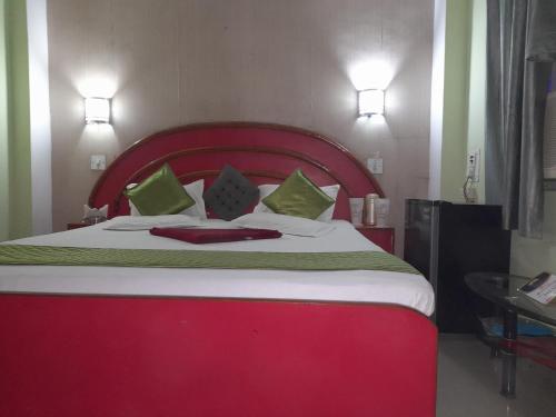 a bedroom with a large red bed with green pillows at Hotel swapanlok, Couple Friendly Hotel in Muzaffarpur