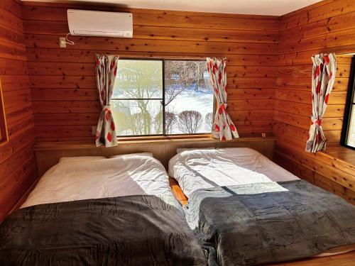 - 2 lits dans une cabane en rondins avec fenêtre dans l'établissement ＨARUNA VILLA 浅間山麓、貸切コテージ、アクセス抜群, à Kita-karuizawa