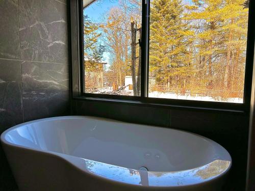 uma banheira na casa de banho com uma janela em ＨARUNA VILLA 浅間山麓、貸切コテージ、アクセス抜群 em Kita-karuizawa