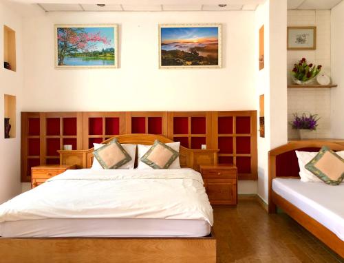 a bedroom with two beds and two paintings on the wall at The One Home Đà Lạt in Da Lat