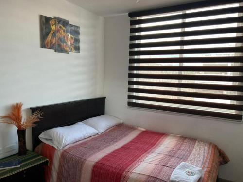 - une chambre avec un lit et une grande fenêtre dans l'établissement Hostal Aly, à Otavalo
