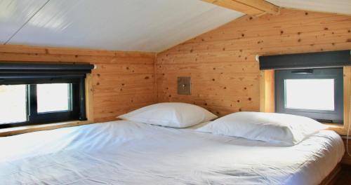 uma cama num quarto de madeira com duas almofadas em Tiny house eco resort em Estevais